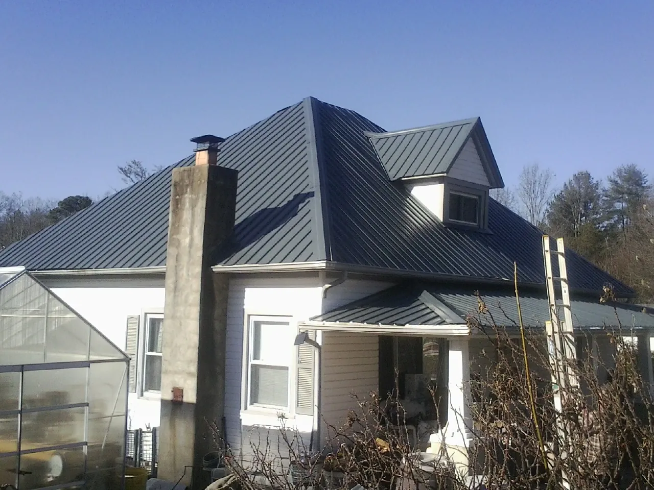 Dark blue standing seam metal roof on a white farmhouse with dormer — Slate & Tile Roof Repair by Roofing Brothers in Kingman