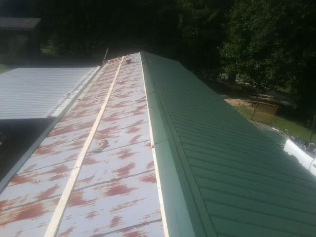 Old rusted panels beside newly installed green metal roofing — Wind Damage Roof Repair by Roofing Brothers in Kingman