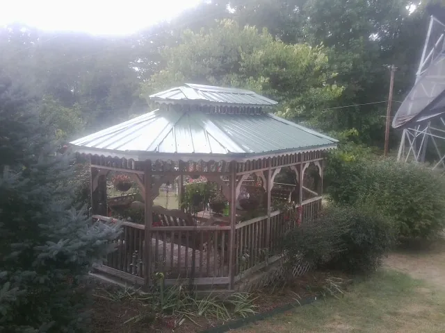Green metal roof on a backyard gazebo surrounded by garden beds in Kingman