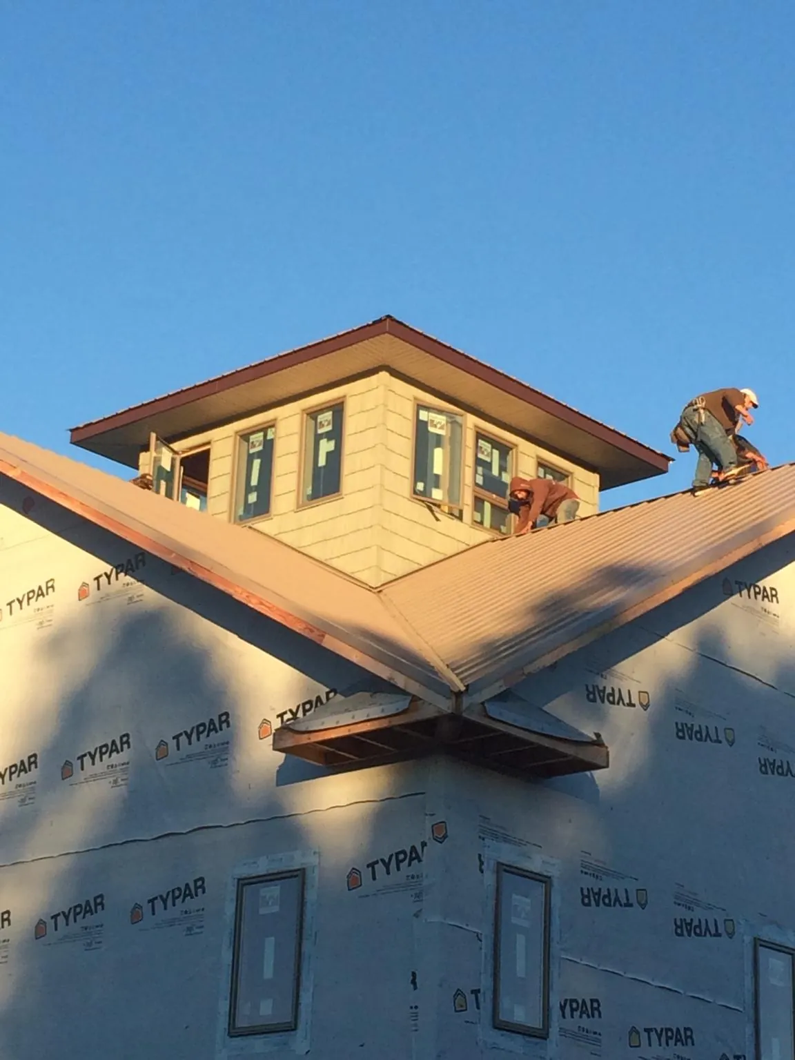 Roofers working around a rooftop cupola on a new metal roof at sunset — Roof Waterproofing in Kingman by Roofing Brothers